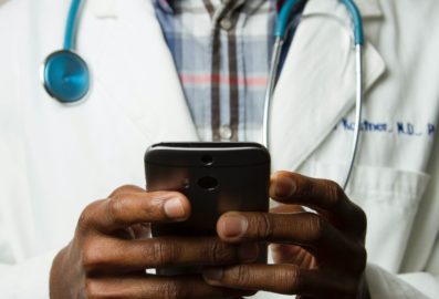 doctor wearing white coat holding mobile phone
