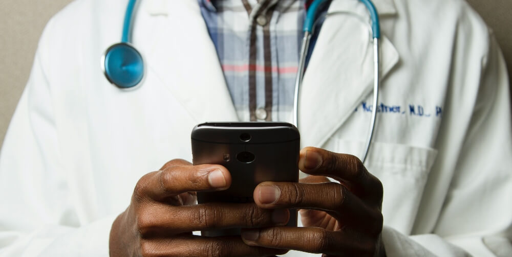 doctor wearing white coat holding mobile phone