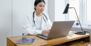 nurse wearing white on a laptop