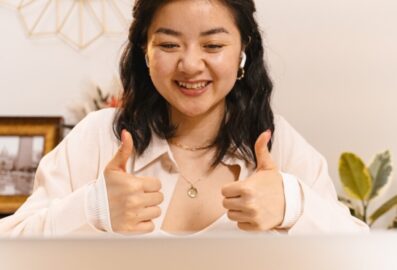 woman smiling with thumbs up to computer screen